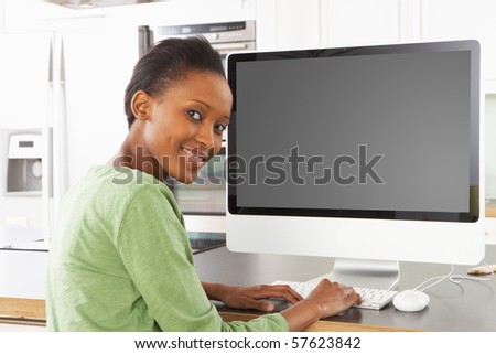 Young Woman Using Computer In Modern Kitchen
