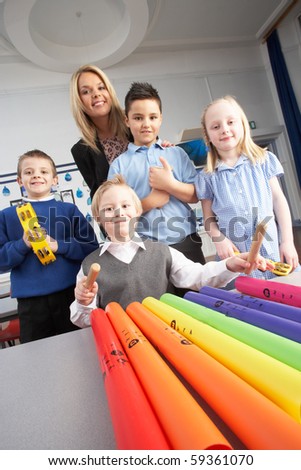 Group Of Primary Schoolchildren And Teacher Having Music Lesson In Classroom