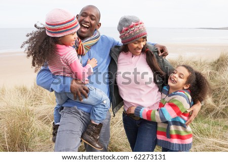 Family Walking Along Dunes On Winter Beach