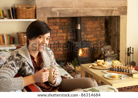 Young woman having tea by fire
