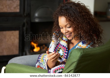Young woman sitting by fire with phone