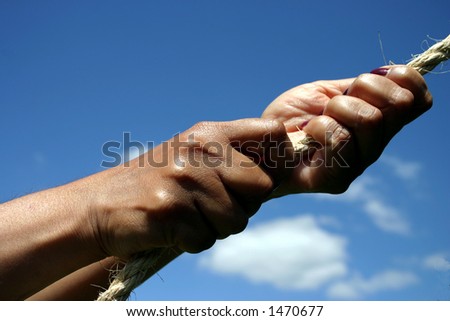 Conceptual image - hands pulling on a rope, blue sky background.  Might signify strength, pulling power, determination, teamwork etc.