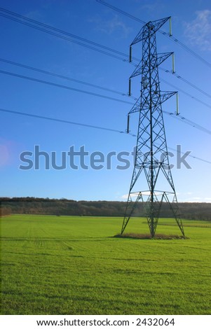 British electricity pylon carrying national grid high voltage power cables, middle of a farmers field