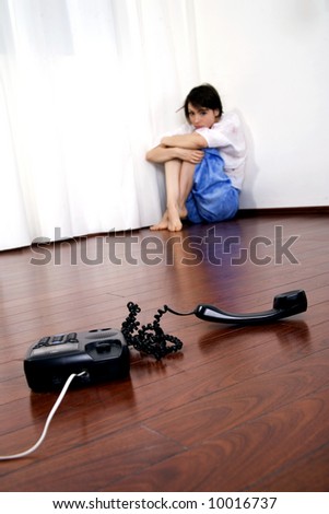 Woman sitting in the corner of the room, phone in front.
