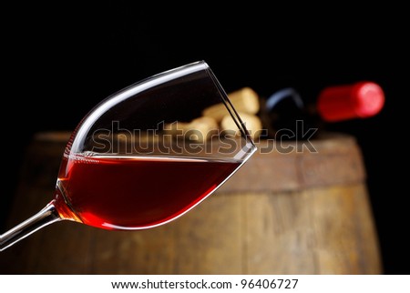 The bottle of red wine and glass and barrel