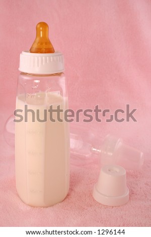 baby bottle full of milk or formula, over pink background