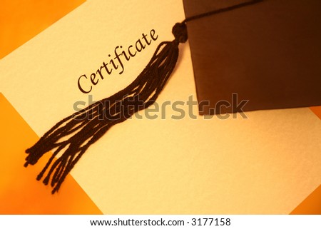 certificate printed on a yellowish grainy textured paper and a black graduation cap on yellow-orange background, top view