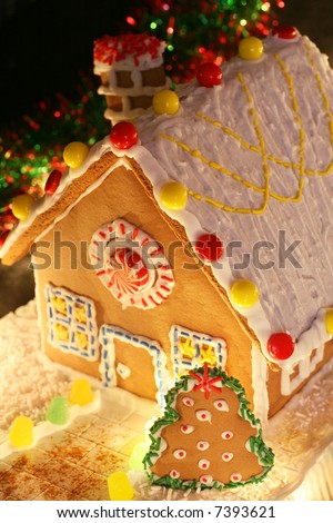 festively lit homemade gingerbread house with Christmas tree and decorations