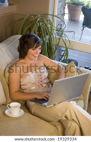 Young woman on couch chatting on laptop