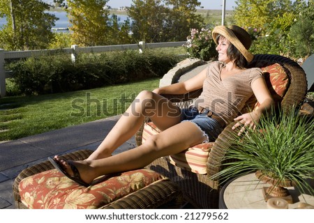 Woman sitting on a patio chair relaxing at home by the lake