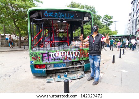 ISTANBUL - JUNE 08: Man with mask in front of damaged bus during protests on June 08, 2013 in Istanbul, Turkey. Guy Fawkes masks widely used and became a symbol of protests in Turkey.