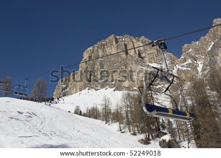 Empty chair lift in a ski resort with mountains and blue sky in the background. Val gardena, Dolomites, Italy.