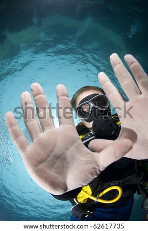 Adult male scuba diver showing the palms of his hands underwater. Focus on the divers\' face. Ras Ghozlani, Sharm el Sheikh, Red Sea, Egypt.