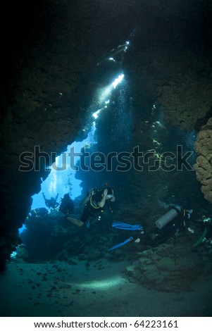 Scuba divers exploring the inside of an underwater cave. Jackfish alley, Ras Mohamed National Park, Red Sea, Egypt.
