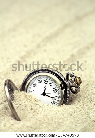 Antique pocket watch buried in sand