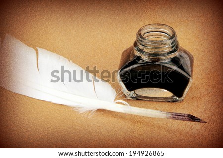 Quill pen and ink bottle on brown background. Vintage style image.