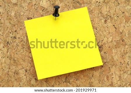 Yellow note paper on cork board. Macro image.