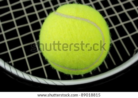 Tennis racket and tennis ball on black background
