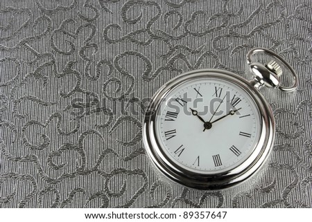 Silver pocket watch on silver background