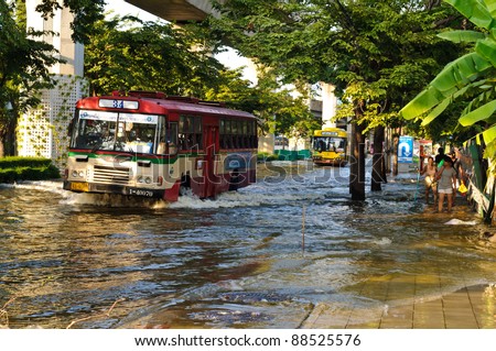 BANGKOK - NOVEMBER 10 : Buses drive on a flooded road and people walk pass a flooded pavement near saphan kwai area on November 10, 2011 in Bangkok.