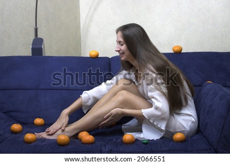 woman sits on a sofa with tangerines