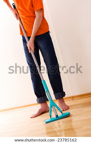 The teenager in an orange T-shirt washes a floor