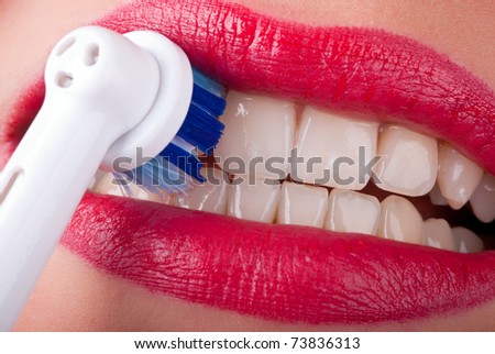 white teeth are brushed with an electric toothbrush