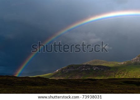 rainbow with dark sky over a meadow