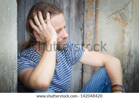 Close-up of a depressed man sitting in an old doorway.