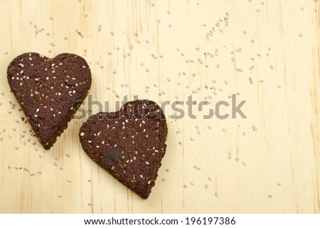 Healthy homemade dark chocolate chia seed love heart cookies on a wooden background