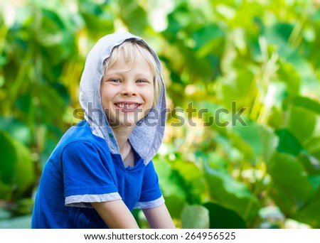 Portrait of a smiling, healthy child out in nature next to a Lilly pond