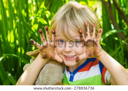 Cute child playing in garden with dirty hands