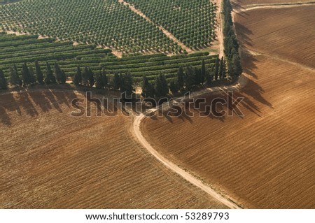 Aerial View of winding Dirt road crossing Plowed Field, in reddish land in the countryside ,Israel