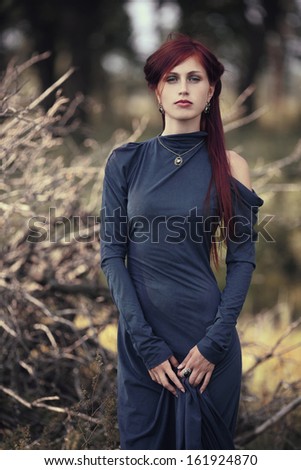 red-haired girl in a long blue dress in the forest