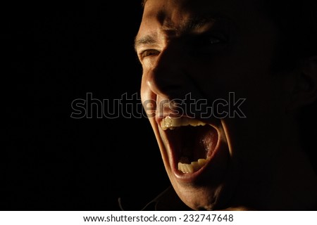Face furiously screaming man on a black background
