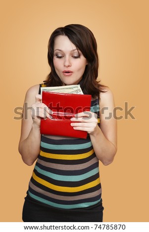 The girl holds a purse with money and surprised