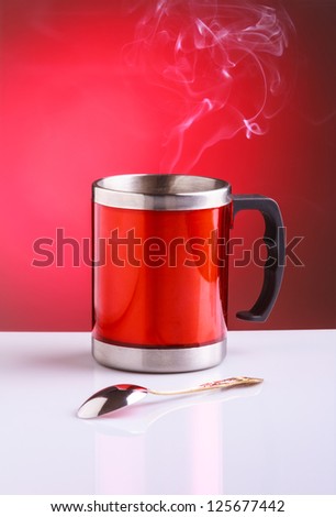 Modern red travel mug with hot tea and spoon