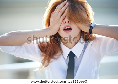 Delightful young woman closed her eyes with both hands / excited brunette girl in a shirt and tie closes her eyes with her hands