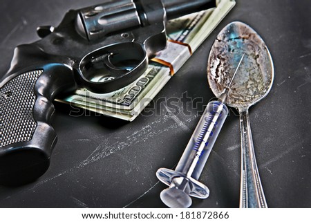 Illegal tools / studio photography of a gun, syringe, spoon and money on black background