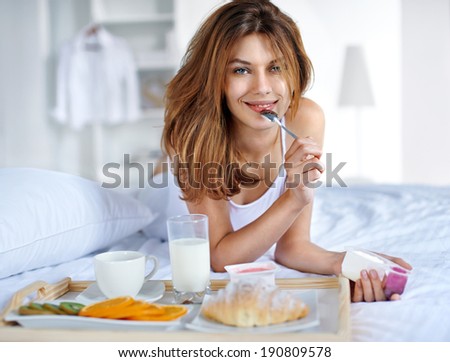 Healthy eating / happy young woman having breakfast in bed