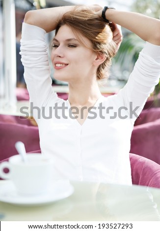 Hands behind head / photo of beautiful woman sitting in a coffee house
