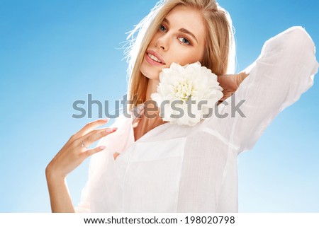 Posing woman / portrait of happy smiling girl with white flower in her hand on blue background