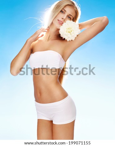 Sexy young woman with flower / portrait of happy smiling girl with white flower in her hand on blue background