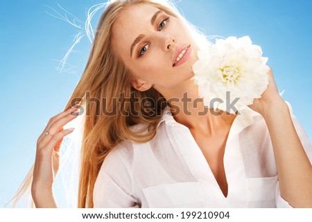 Young woman holding white peony flower / portrait of happy smiling girl with white flower in her hand on blue background