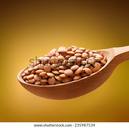 Lentil in a wooden spoon / beans on wooden spoon isolated on golden background