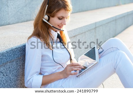 Smiling pretty business woman with headset / outdoors photography of young Caucasian woman wearing white shirt with black tie