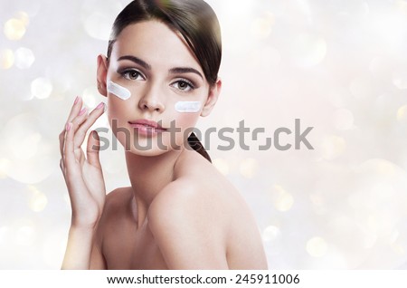 Skin care woman putting face cream / photoset of attractive brunette girl on blurred gray background with bokeh