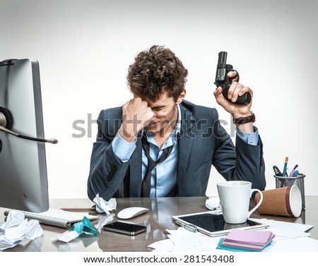 Young businessman with gun wants to commit suicide / modern office man at working place, depression and crisis concept