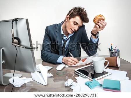 Young business man talking on the phone and writing down at his working place