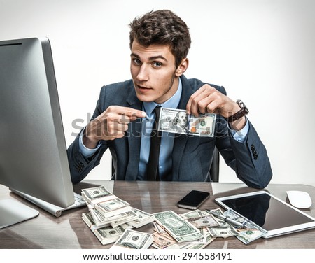 Entrepreneur showing his motivation earnings, profit, income, gain, benefit, margin / modern businessman at his desk with computer and a lot of money